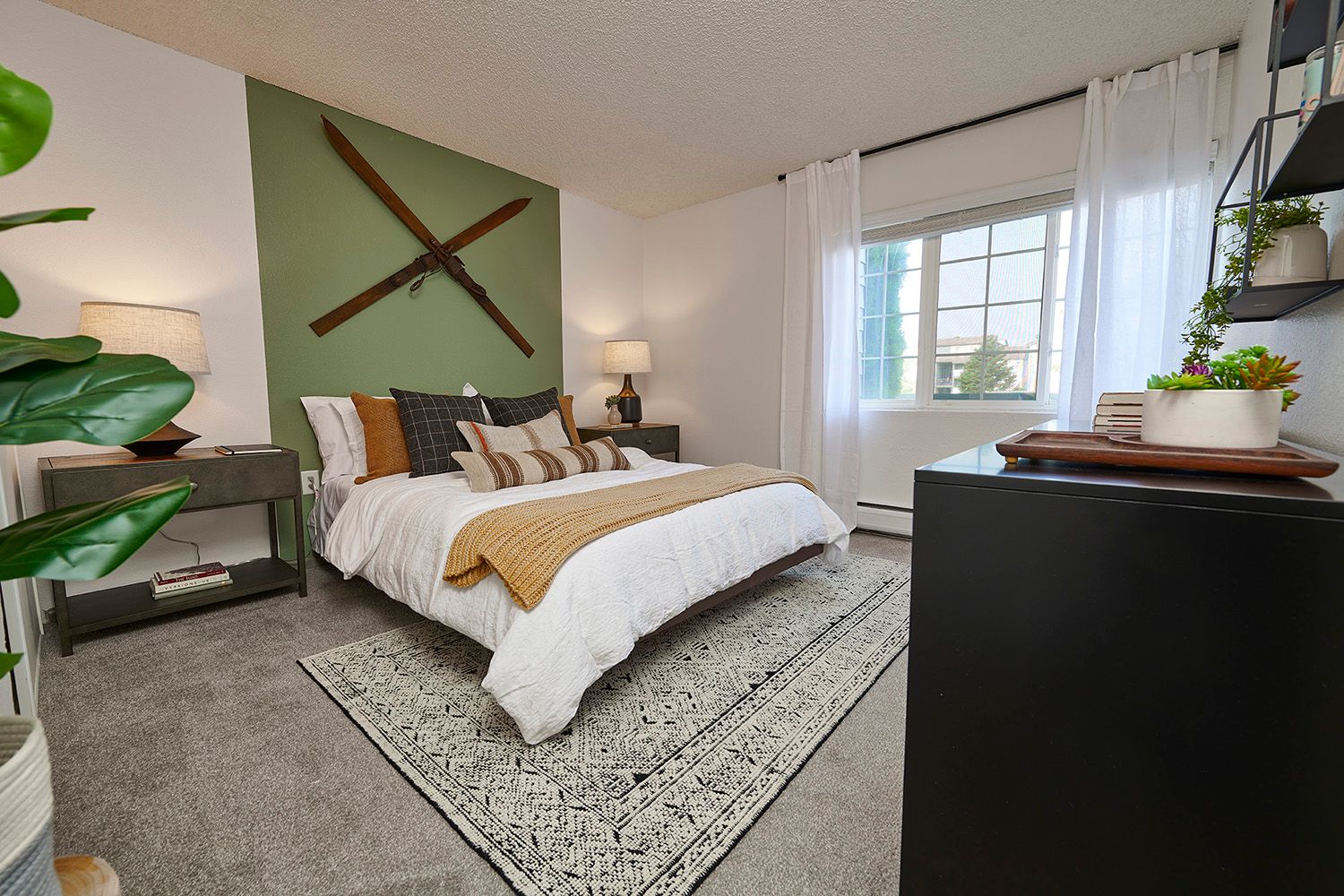 Carpeted bedroom with large windows and green accent wall