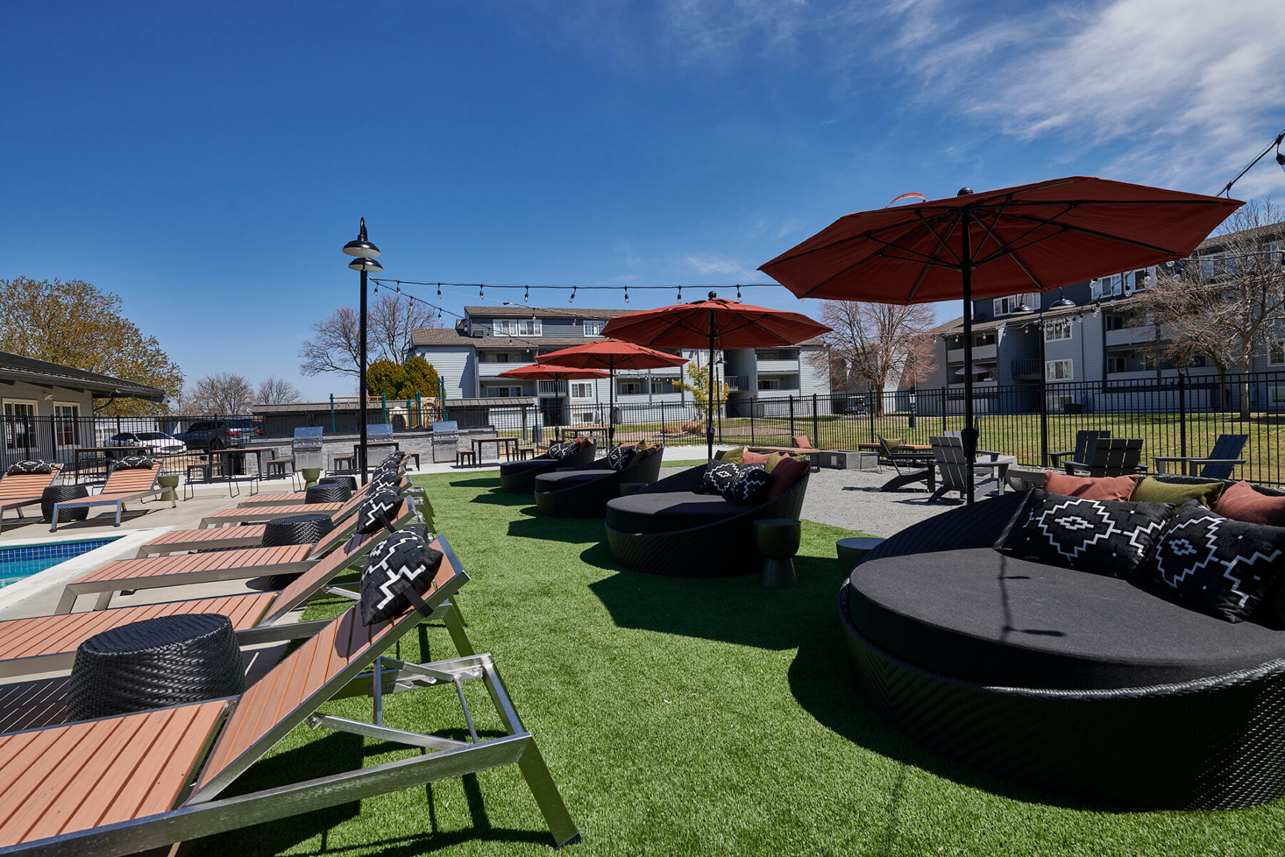 poolside couches, chairs, and lounge furniture on fake grassy area.