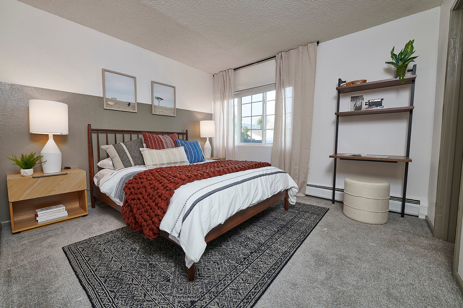 bedroom with grey carpet, queen bed , one large window and wooden side table