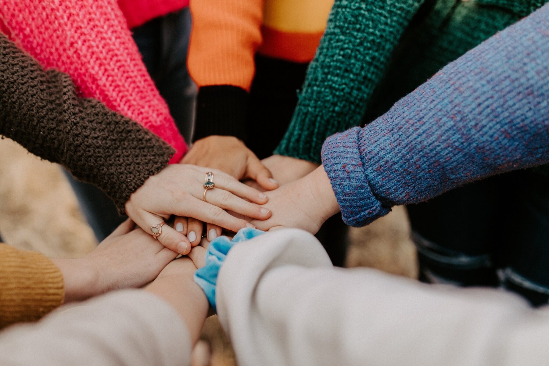 Group of people standing in a circle placing their hands together in the middle